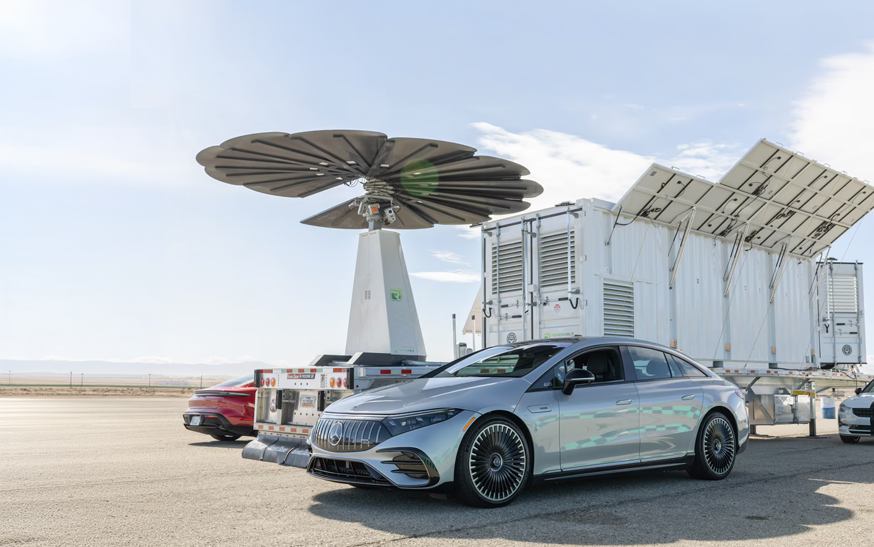 SmartFlower on top of a trailer in the middle with several cars parked on both the left and right