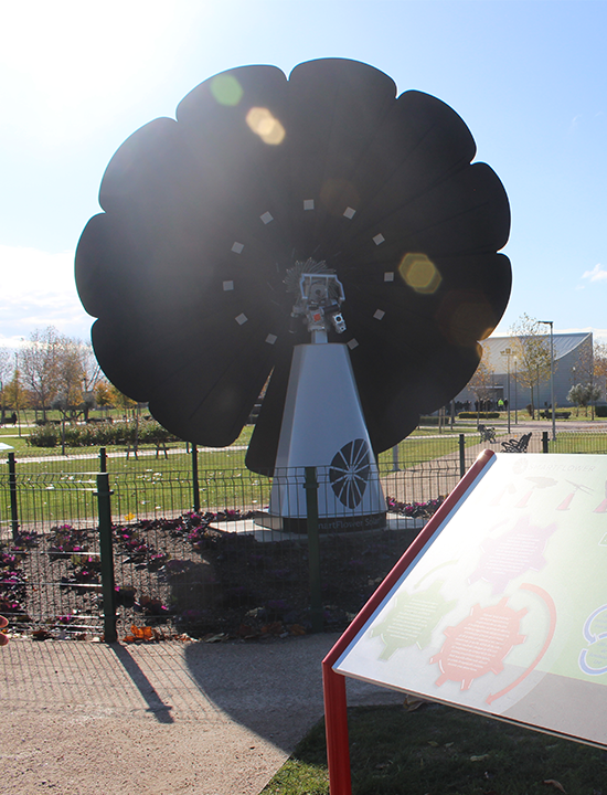 SmartFlower solar panel installed on university campus with educational sign and landscaped park