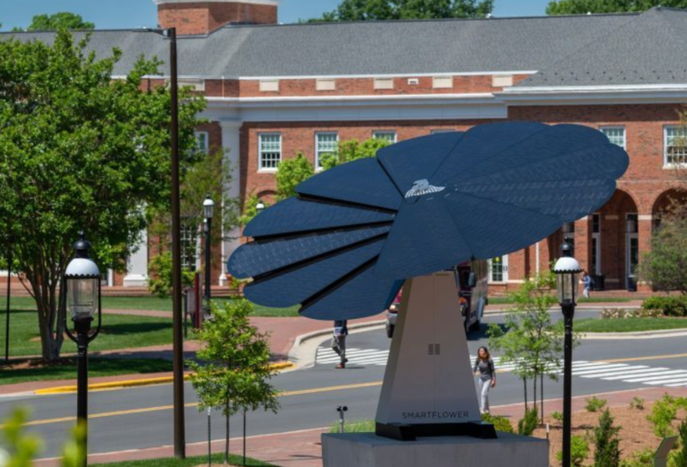 SmartFlower sitting on a podium and in the background is Elon University buildings