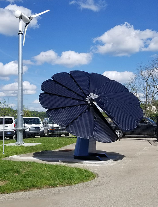 Renewable energy setup with Smartflower solar array and wind turbine against blue sky backdrop