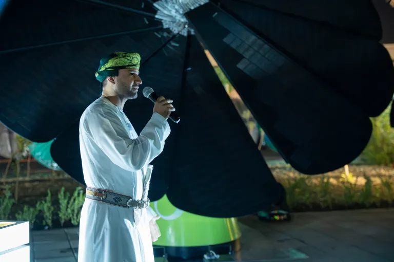 Grand opening of Oman Sustainability Academy with a man standing to the left with a microphone with a SmartFlower behind