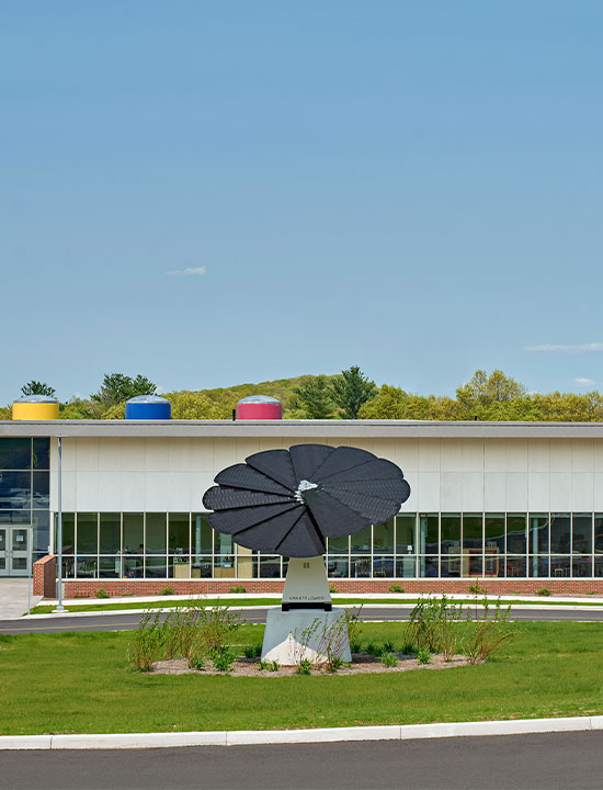 Flower-shaped solar energy system in front of an educational facility with American flag